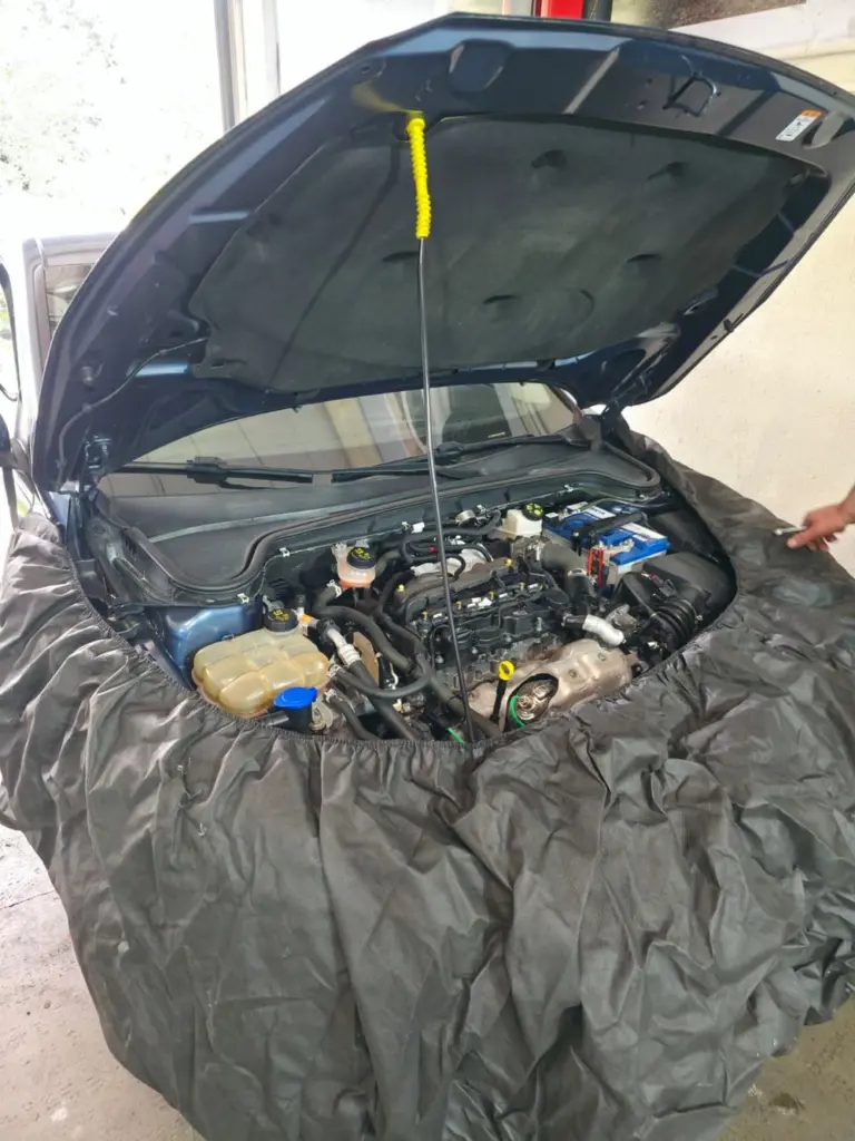 Servis alanında açık kaputlu, korumalı çamurluklu araç
